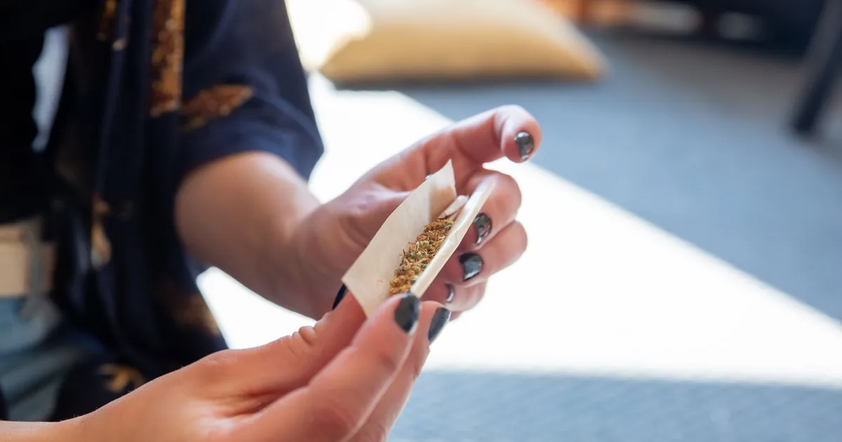 Hands rolling flower into a rolling paper