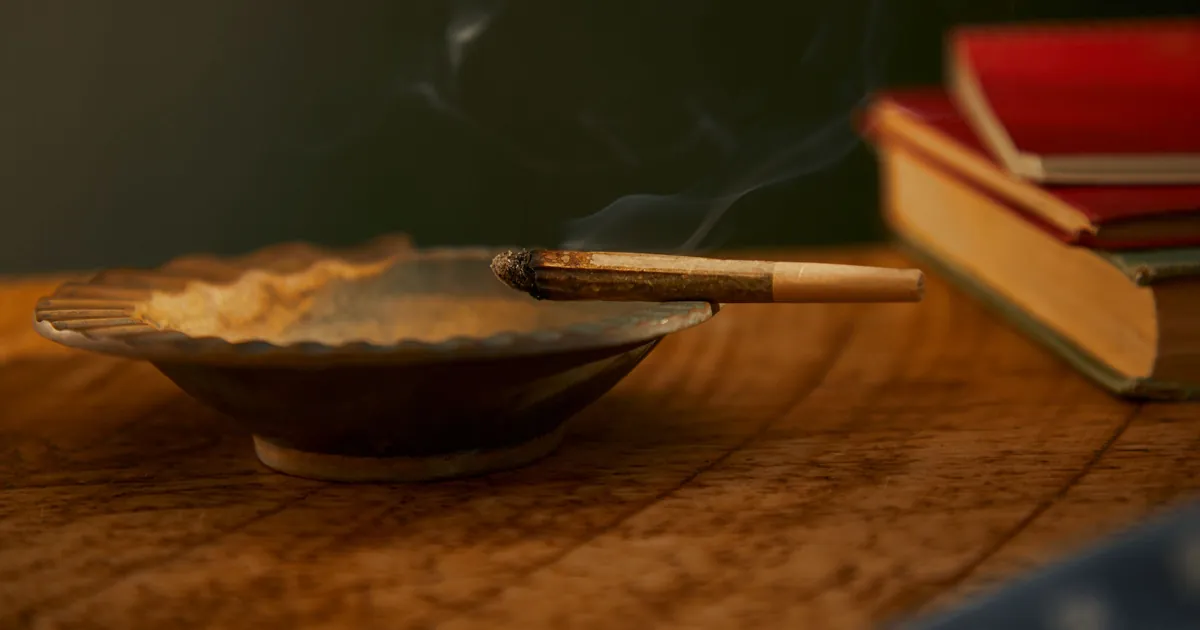 A lit joint resting on an ashtray with smoke rising